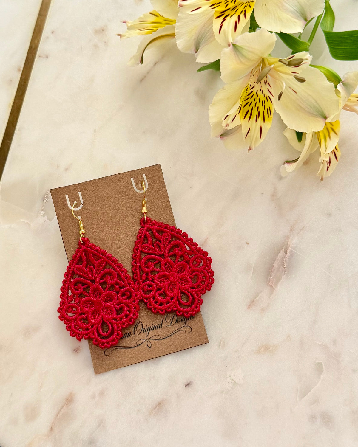 Red and gold teardrop earrings made from embroidery on display card